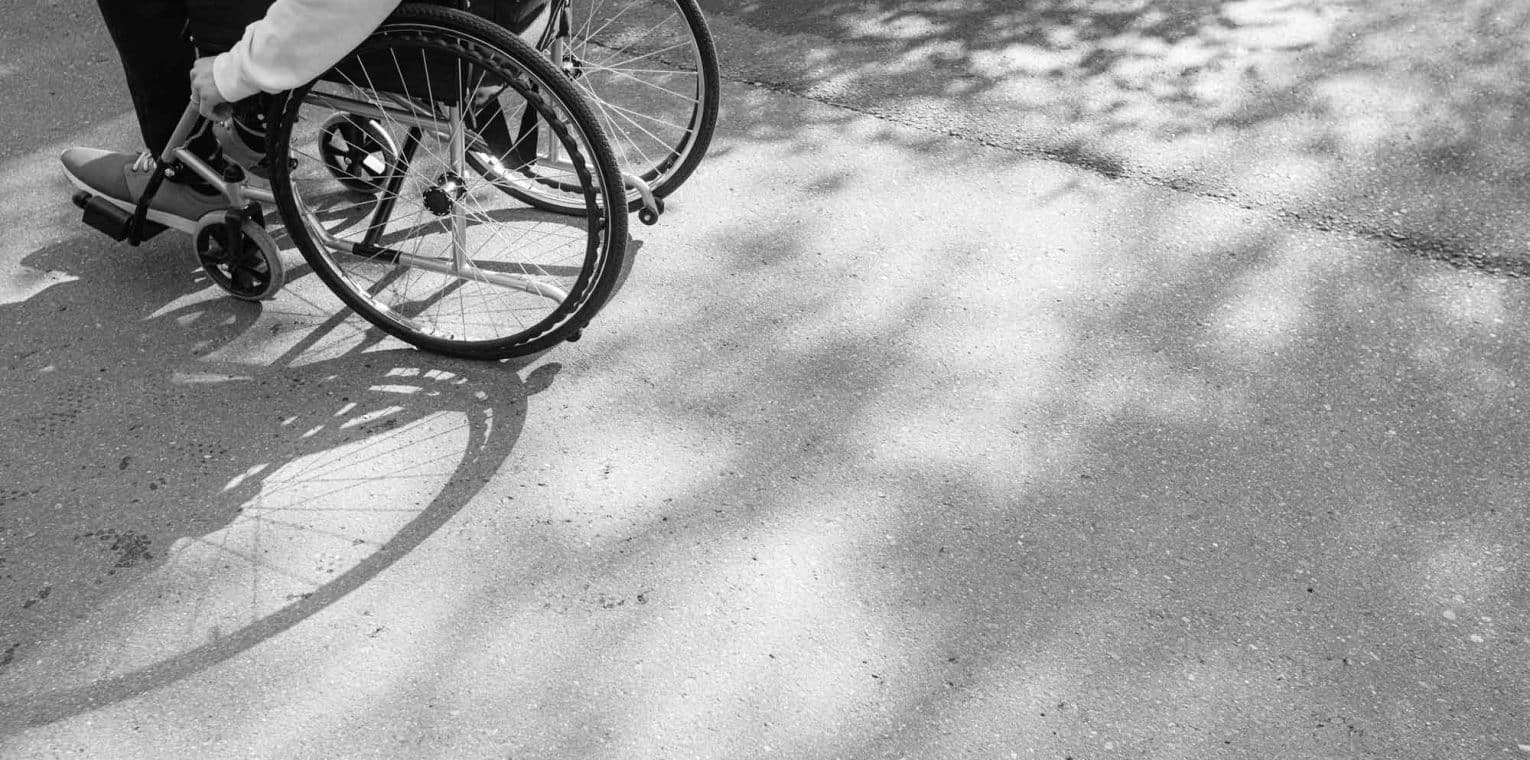 Pedestrian in wheelchair on sidewalk.